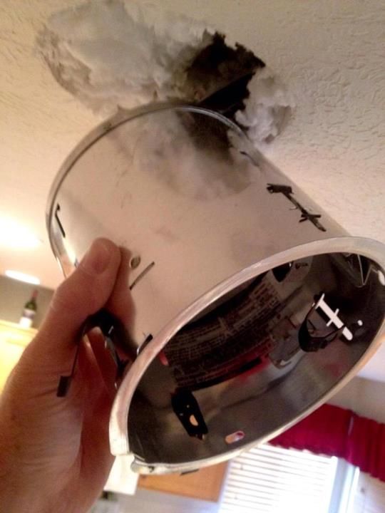 An old recessed can light pulled out of a textured ceiling
