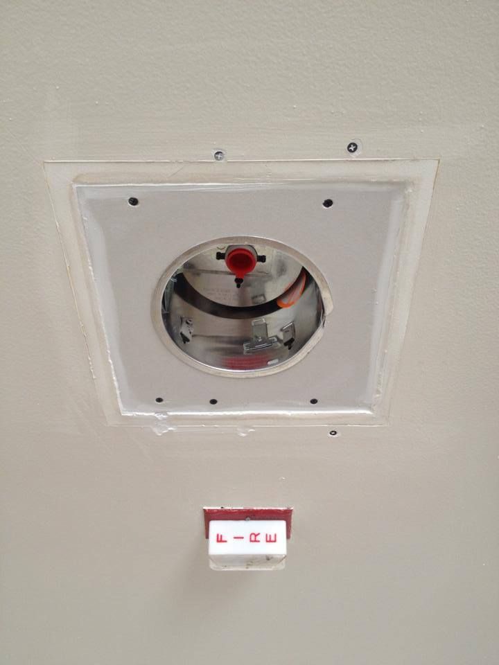 A recessed can set in a ceiling patch above a FIRE sign