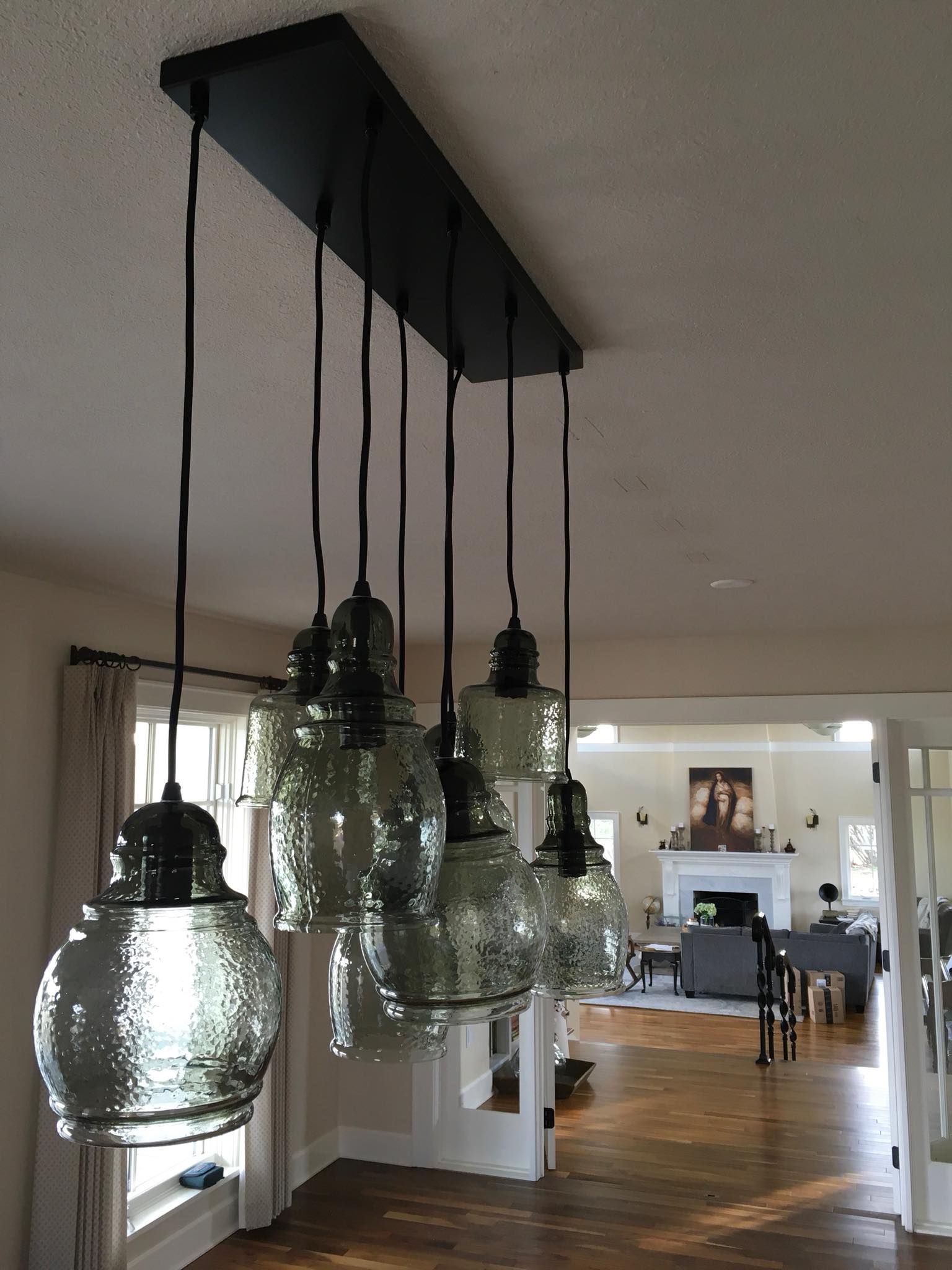 Seven hammered-glass pendants hung from one black canopy over a dining room