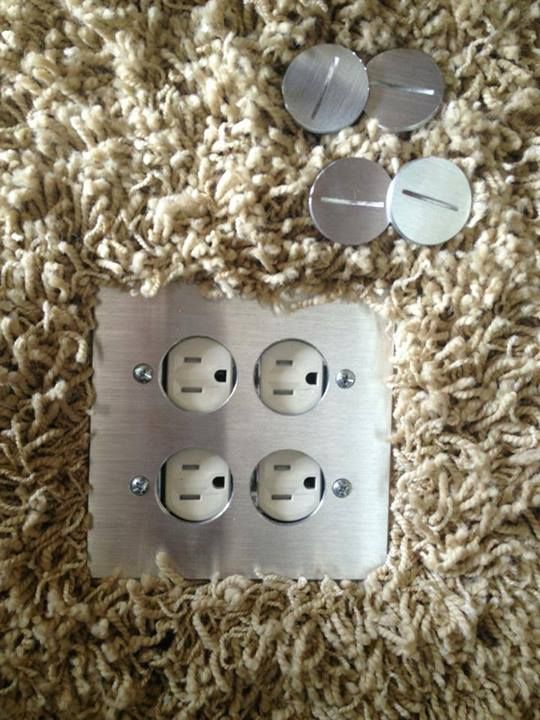 A brushed-steel four-plug floor outlet in carpet