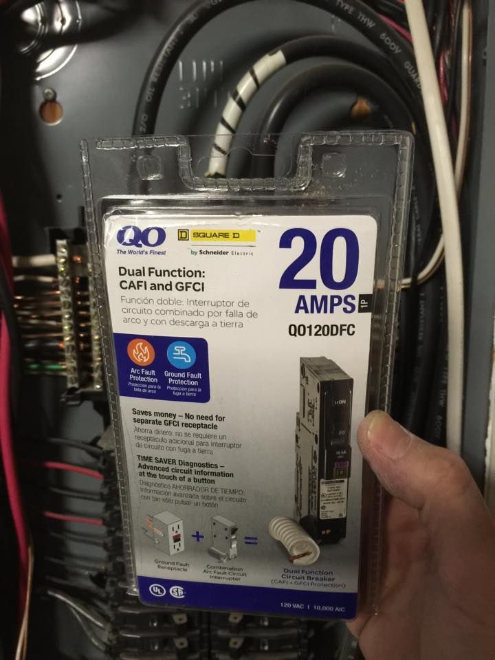 A packaged dual-function breaker held in front of an open panel