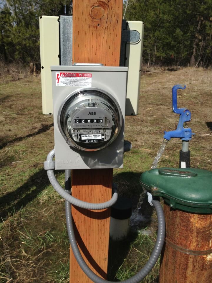A meter on a wooden post by a well hydrant