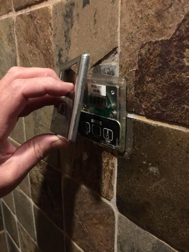 A hand holding a chrome cover at a steam control